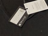 a black t - shirt with a tag on it sitting on a table