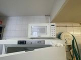 un micro-ondes blanc posé sur une machine à laver dans une cuisine