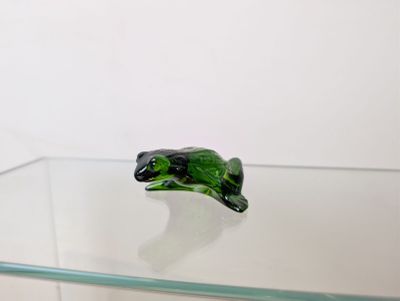 une grenouille en verre posée sur une table en verre
