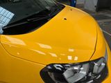 a close up of a yellow car parked in a parking lot
