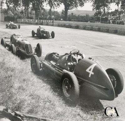 une photo en noir et blanc montrant un groupe de voitures sur un circuit automobile