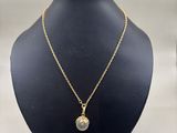 a gold plated necklace with a round pendant on a mannequin