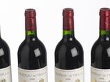six bottles of red wine lined up in a row on a white surface