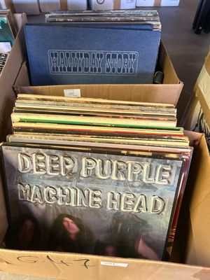 une boîte en carton ouverte, remplie de divers disques, posée sur une table