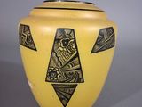 a yellow vase with a black design on it