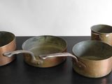 trois casseroles et des cuillères posées sur une table