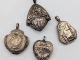 a group of four silver pendants of various shapes and sizes