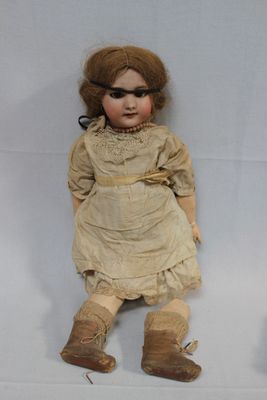 two old dolls sitting next to each other on a white surface
