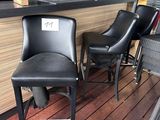deux chaises noires posées devant un bar, avec un ventilateur en arrière-plan