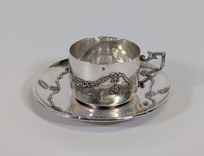 une tasse à thé en argent et sa soucoupe, posées sur une soucoupe