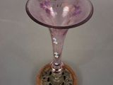 a pink glass vase with a wooden base on a table