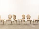 four chairs in a room with a white wall and a clock on the wall