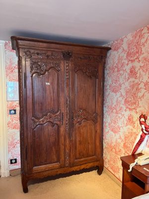 a wooden armoire in a bedroom with a red and white wallpaper