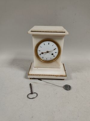 a small white clock with a gold face and a key