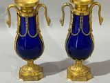 two blue vases with gold handles on a white surface