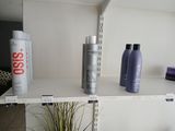 deux flacons de produits capillaires posés sur une étagère à côté d'une plante en pot