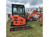 an orange excavator is parked in a field with other equipment