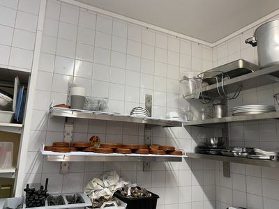 des étagères sur lesquelles sont posées des casseroles et des poêles, dans une cuisine carrelée de blanc
