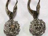 paire de boucles d'oreilles anciennes en argent, ornées d'un motif floral sur fond blanc