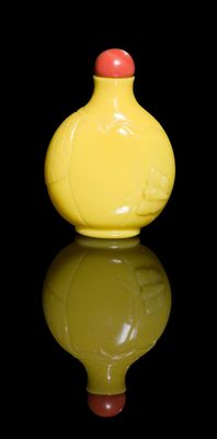 un vase jaune avec un couvercle rouge posé sur une surface noire