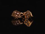 un gros plan sur une paire de boucles d'oreilles en or posées sur une surface noire