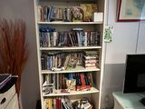 a white bookcase filled with books in a living room