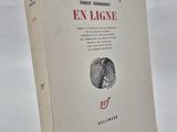 un vieux livre posé sur une table blanche à côté d'un mur blanc