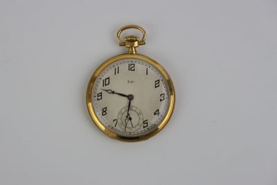 une montre de poche en or sur une surface blanche