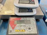 three electronic scales sitting on top of a blue table in a warehouse