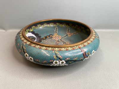 un petit bol bleu orné de fleurs, posé sur une table