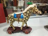 un cheval en bois posé sur une charrette en bois