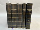 five old books are lined up in a row on a white surface
