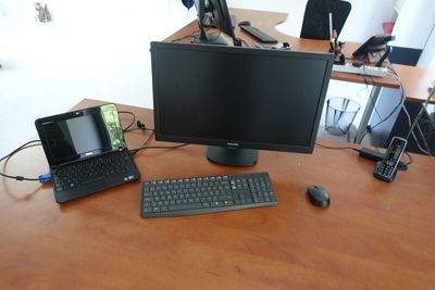 a computer desk with a laptop, monitor, keyboard, mouse and cell phone