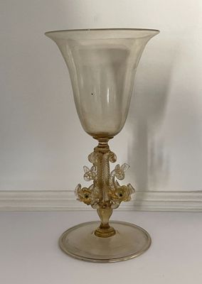 un gobelet en verre posé sur une table devant un mur blanc