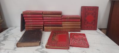 beaucoup de vieux livres posés sur une table, avec une horloge en arrière-plan