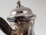 a silver tea pot with a wooden handle on a table