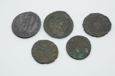 quatre pièces romaines, dont l'une représente une tête et deux d'entre elles un visage
