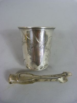 une tasse en argent et une cuillère sur une table blanche