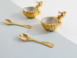 three gold spoons and a bowl with a giraffe on it