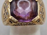 gros plan d'une bague avec une pierre violette entourée de diamants