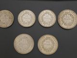 six different types of coins on a table with a knife