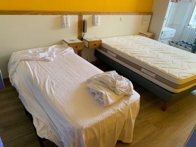 deux lits dans une chambre aux murs jaunes, recouverts de draps blancs