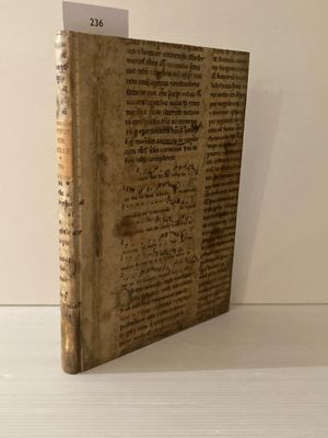 un vieux livre posé sur une table blanche à côté d'un mur blanc