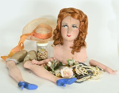 a doll sitting on the ground with a hat and other items