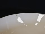 a white bowl sitting on a table with a black background