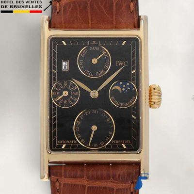 une photo d'une montre en or avec un cadran noir, montée sur un bracelet en cuir marron