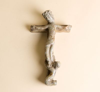 une croix en bois accrochée au mur à côté d'un morceau de bois