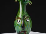 a green vase with a face on it on a table