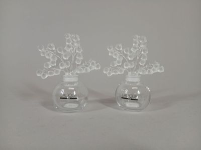 two clear vases with flowers in them on a white surface