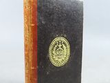 un petit livre orné d'un emblème doré